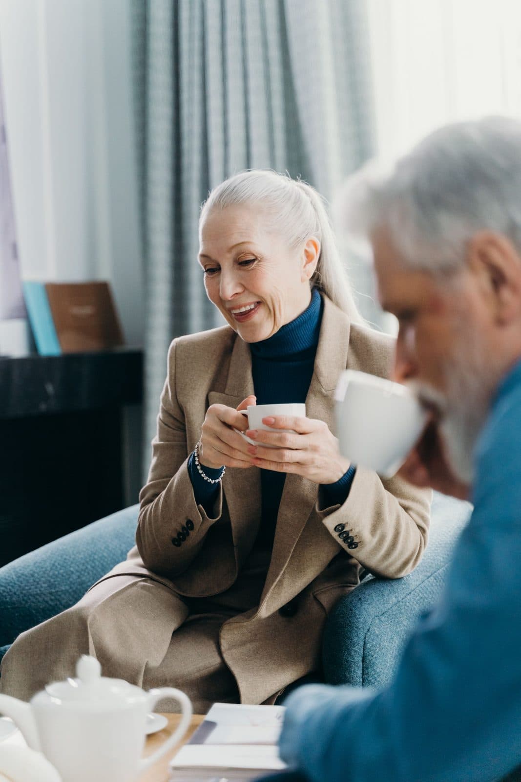 A couple in their sixties talking over coffee in a bright, calm room