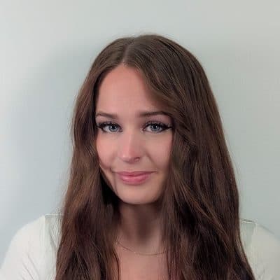 Cierra Dills, in a white top, against a pale grey wall